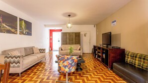 A living room with a herringbone floor, two sofas, a coffee table, and a TV. - Pousada Soft Brooklin (São Paulo)