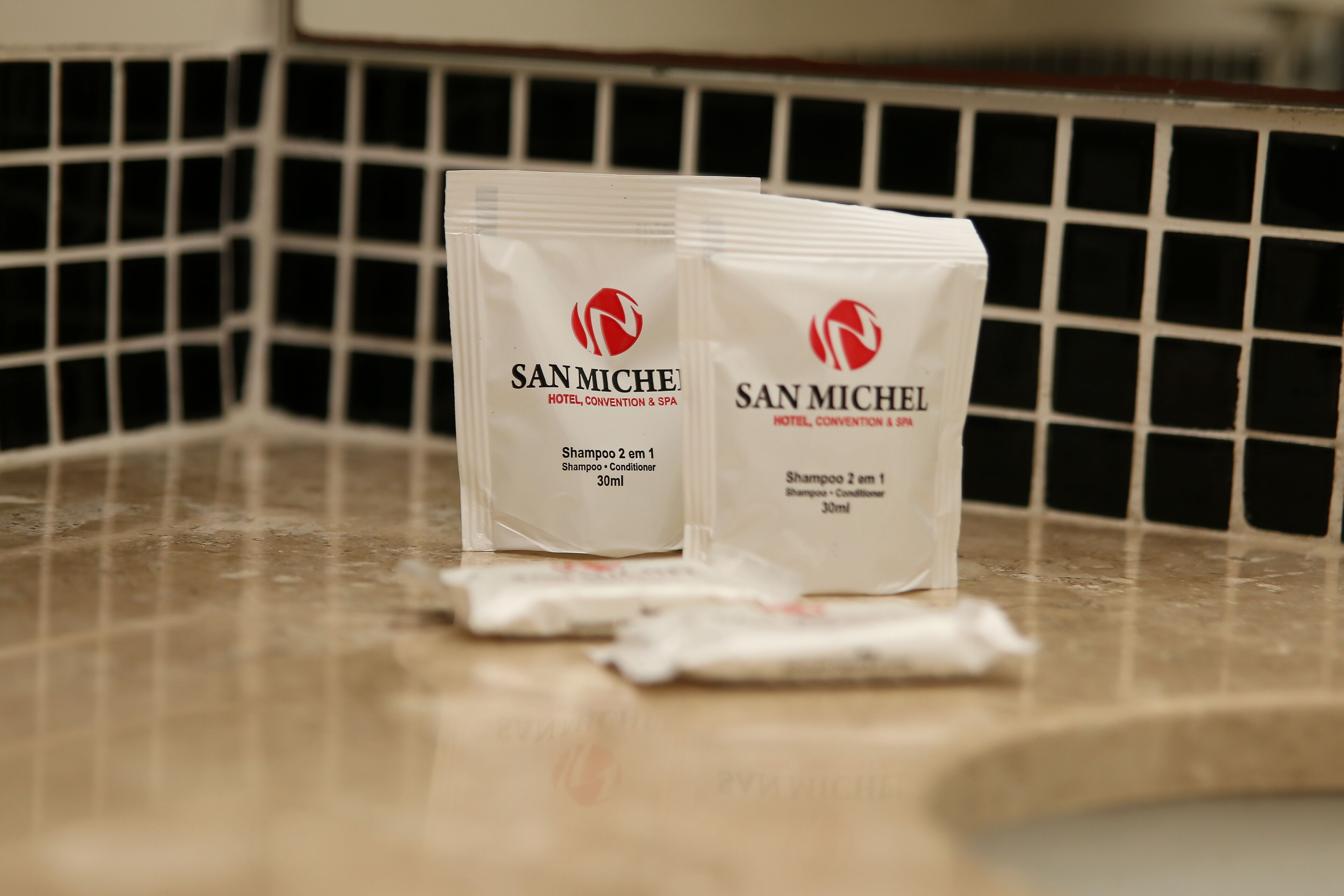 Dois pacotes de shampoo e condicionador da marca San Michel em uma bancada.