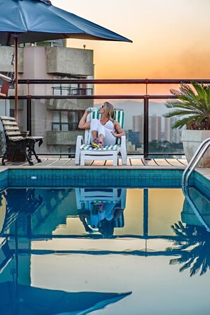 Una piscina al aire libre, sillones reclinables de piscina
