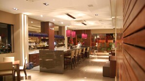 A modern bar area with a counter, seating, and a view of the cityscape. - San Michel Hotel (Taubate)