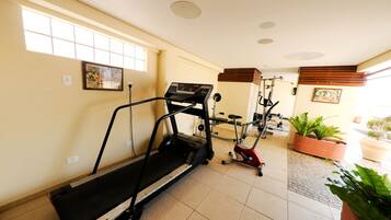 A gym with a treadmill, stationary bikes, and exercise equipment.