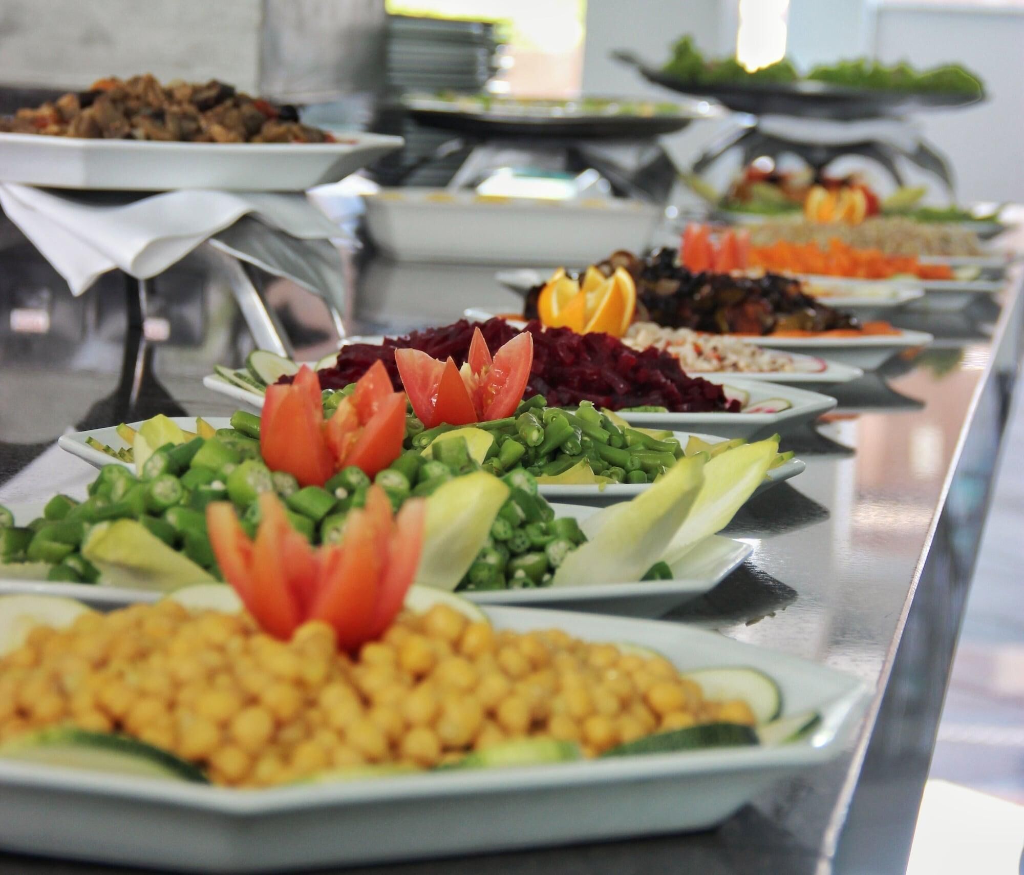 A buffet with various dishes including salads, vegetables, and legumes.