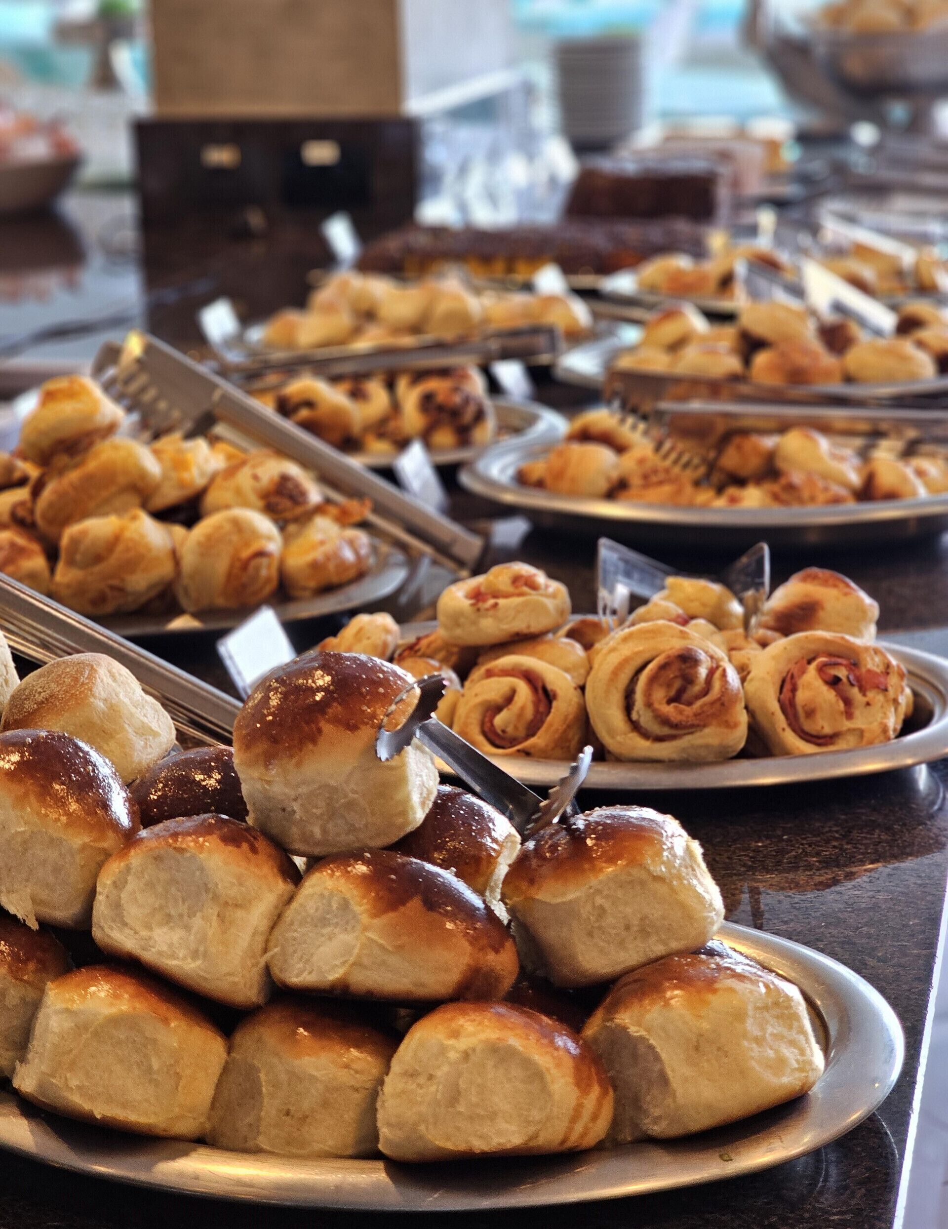 A buffet table with various baked goods, including rolls and pastries.