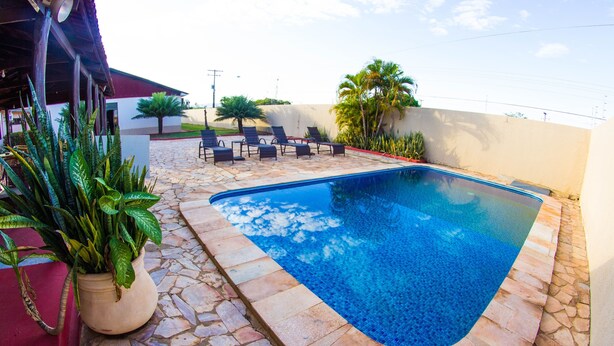Una piscina con baldosas de piedra, rodeada de sillas de descanso y plantas en macetas.