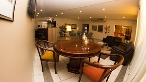 Un comedor con una mesa redonda de madera, cuatro sillas y una planta en maceta.