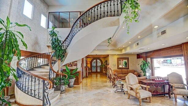 A spacious lobby with a grand spiral staircase, comfortable seating areas, and large windows offering views. - Hotel Fresno Galerías (Torreón)