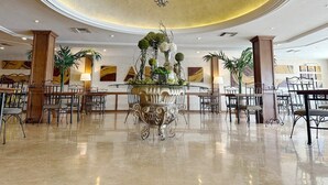 A spacious lobby with a central ornate table, surrounded by chairs, and a chandelier. - Hotel Fresno Galerías (Torreón)