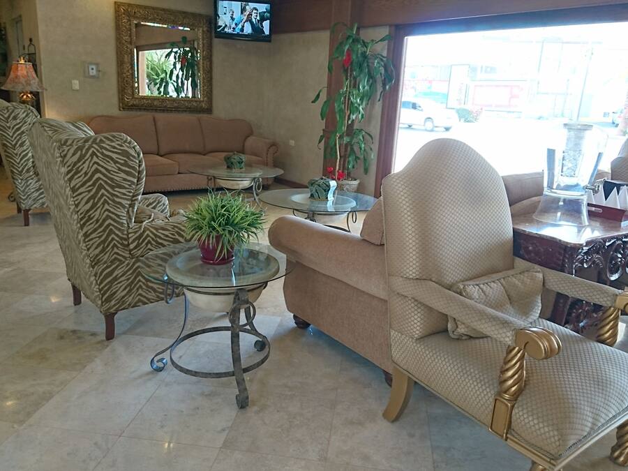 Eine Lobby mit einer Couch, Sesseln, einem Couchtisch, einem Fernseher und einem großen Fenster.
