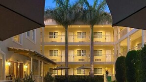A hotel courtyard with a swimming pool, lounge chairs, and palm trees. - Hotel Fresno Galerías (Torreón)