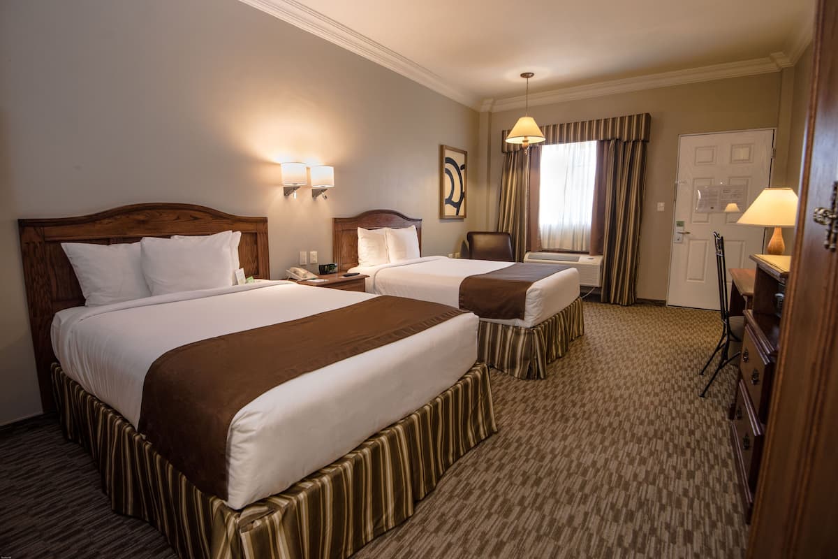 Two large beds with matching headboards and footboards, a nightstand, and a small table with lamps.