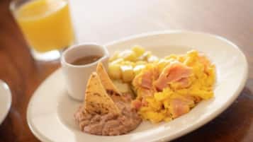 Un plato con huevos revueltos, frijoles refritos y un totopo.