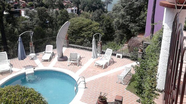 Zona de piscina con sillones de descanso y vistas a un lago y montañas.