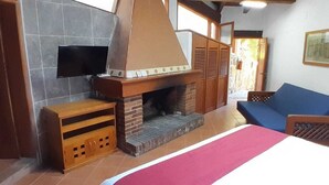 Una habitación con chimenea, televisión montada en la pared y un sofá azul.