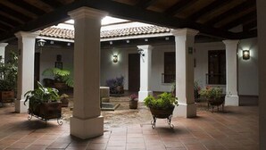 A covered courtyard with tiled flooring, columns, and potted plants. - Posada Santa Rita (Mascota)