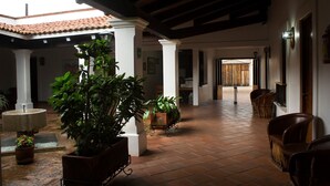 A spacious indoor area with tiled flooring, white columns, and potted plants. - Posada Santa Rita (Mascota)