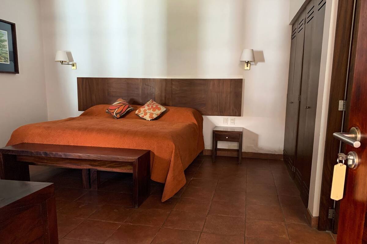 Un dormitorio con cama, mesita de noche, lámpara y armario.