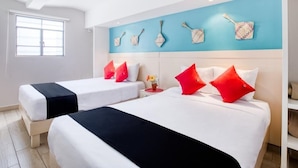 Une chambre d’hôtel avec deux lits, un mur d’accent bleu et des œuvres d’art décoratives.