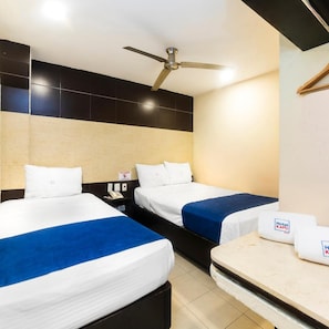 Habitación de hotel con dos camas, ventilador de techo, mesita de noche con teléfono y un cartel que indica que no se permite fumar.