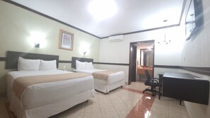 A hotel room with two beds, a desk, a chair, an air conditioning unit, and a mirror. - Hotel Casa Blanca (Chetumal)