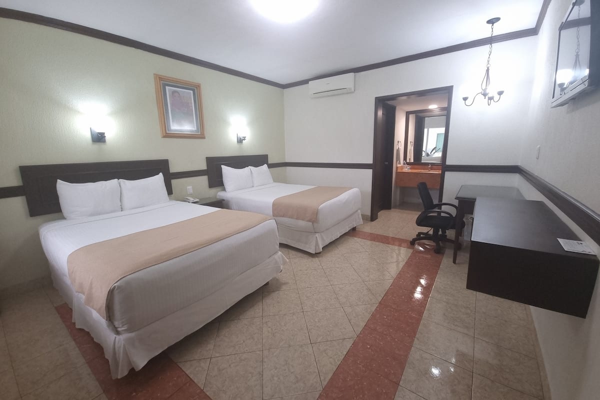 A hotel room with two beds, a desk, a chair, a mirror, and a picture on the wall.