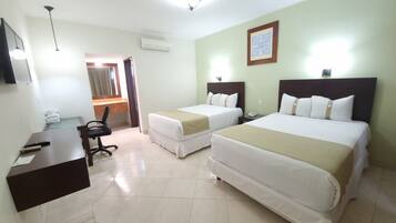 A hotel room with two beds, a desk, a chair, and a bathroom visible through an open door.