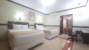 A hotel room with two beds, a desk, a chair, and a mirror.