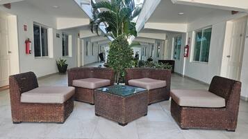A spacious indoor area with wicker furniture, a glass-top table, and a large potted plant.