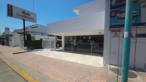 A hotel entrance with a sign for Casa Blanca, a gated entrance, and a warning sign for high voltage. - Hotel Casa Blanca (Chetumal)