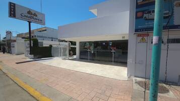 Entrada de hotel con un letrero que dice Casa Blanca, acceso mediante portón y señal de advertencia de alta tensión.