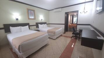 A hotel room with two beds, a desk, a chair, a mirror, and a picture on the wall.