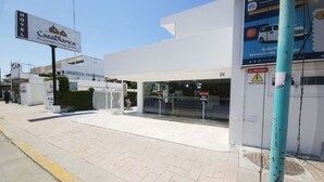 A hotel entrance with a sign for Casa Blanca, a gated entrance, and a visible ATM on the sidewalk. - Hotel Casa Blanca (Chetumal)