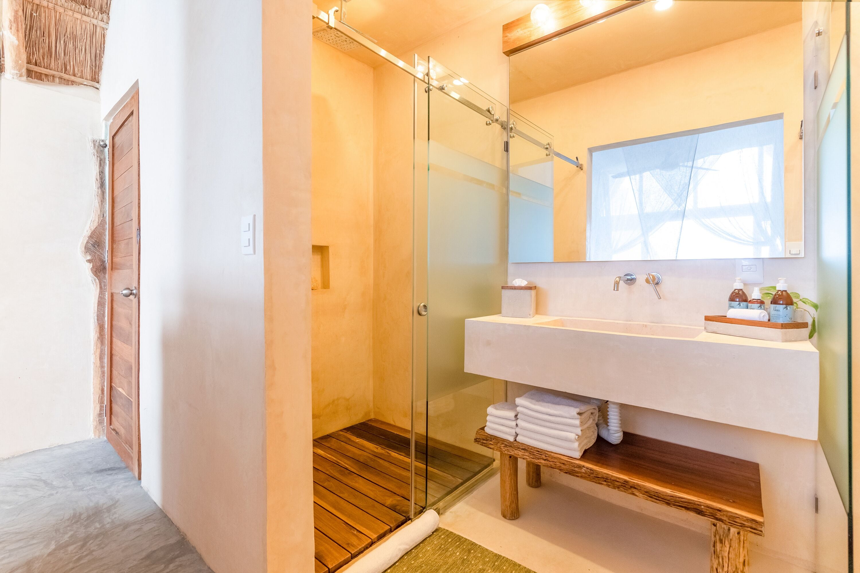 A modern bathroom with a glass-enclosed shower, a wooden vanity, and a large mirror.
