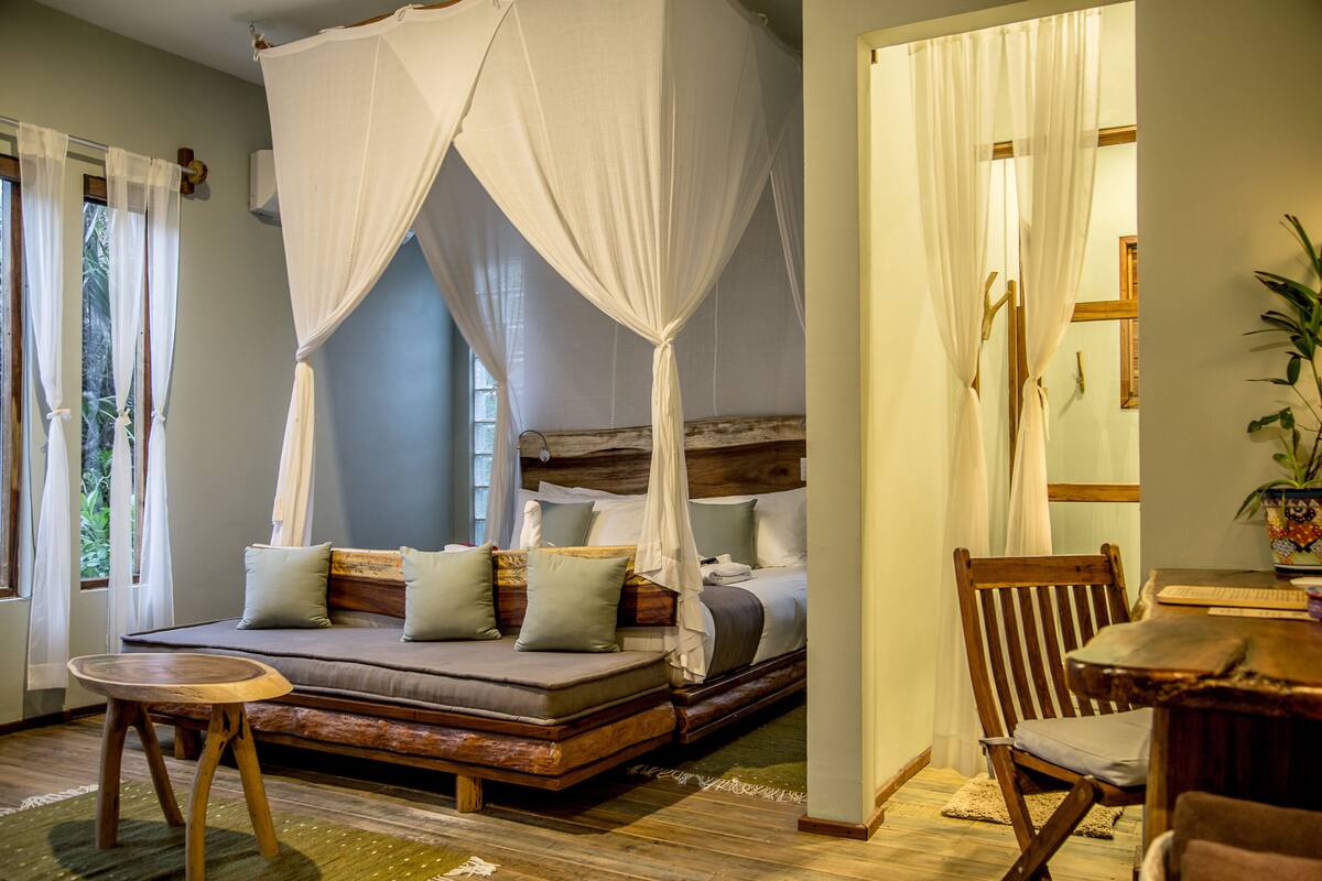 A room with a bed, a wooden bench, and a table.