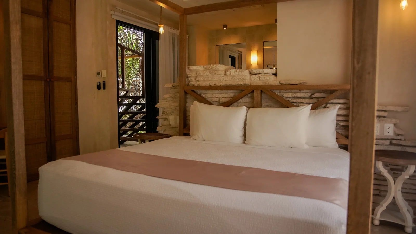A bedroom with a bed, a stone wall, and a wooden ceiling structure.