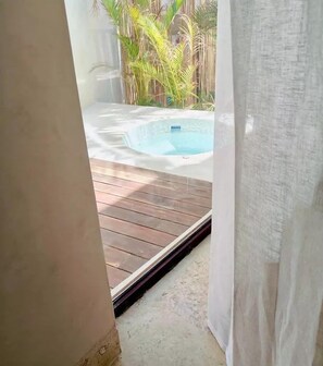 A view of a wooden deck leading to a hot tub surrounded by tropical plants. - Azucar Hotel Tulum    (Tulum)