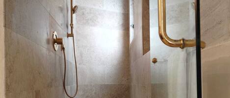 Un espace douche moderne doté d’une porte en verre, d’un banc et d’un pommeau de douche fixé au mur.