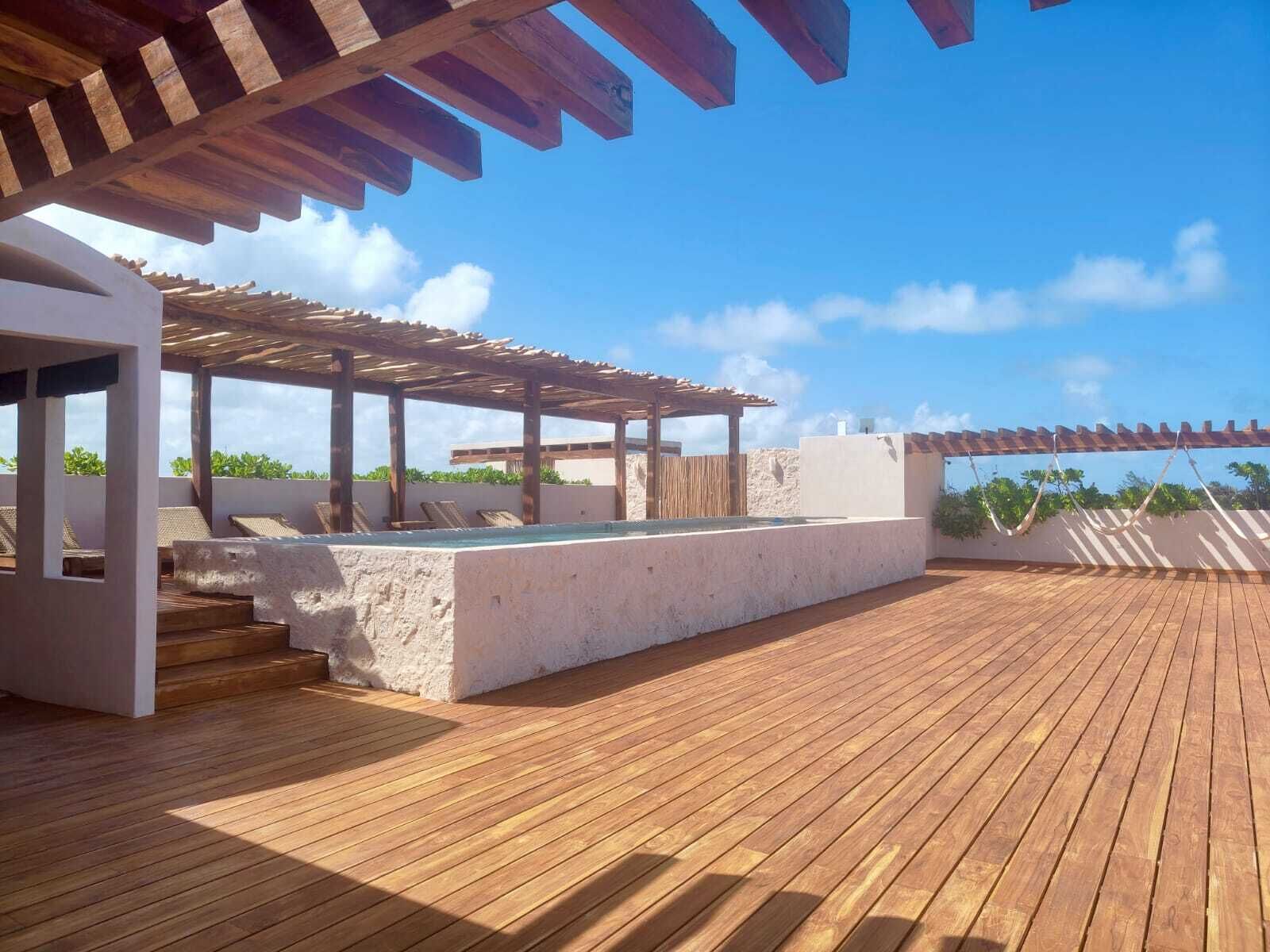 A rooftop terrace with wooden flooring, a pool, and a pergola.