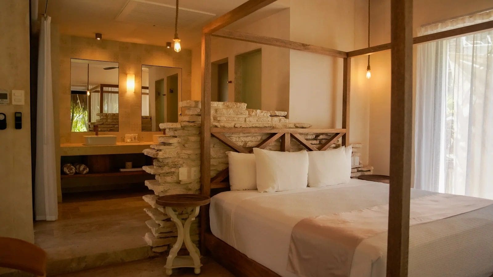 Een slaapkamer met een hemelbed, een stenen muur en een grote spiegel.