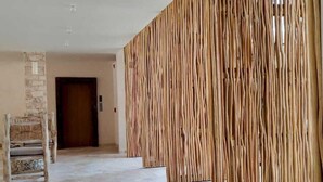 Ein geräumiger Korridor mit einer Steinsäule, einem Holzstuhl und einer Holzvertäfelung.