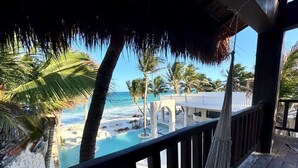 A beach view from a wooden deck with a pool, palm trees, and a clear sky. - Azucar Hotel Tulum    (Tulum)