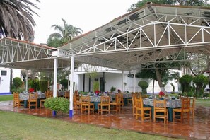 An outdoor dining area with tables and chairs, covered by a metal roof structure. - Hotel GS Jerocs Tlaxcala (Tlaxcala)