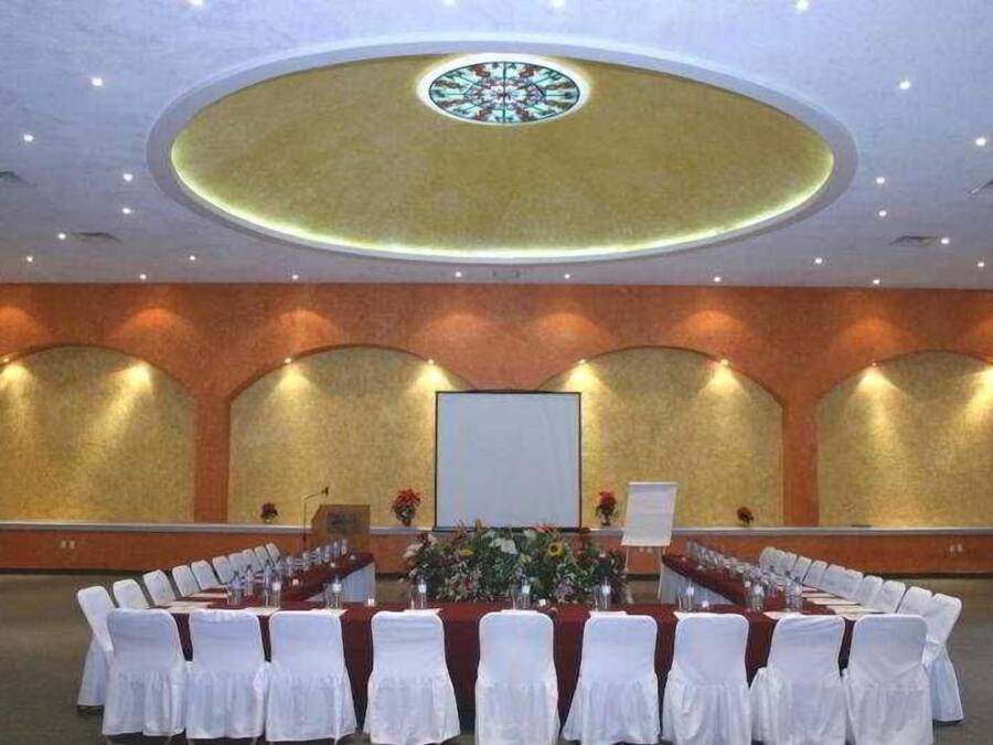 Ein Konferenzraum mit einem langen Tisch, weißen Stühlen und einer Bühne mit einem Rednerpult.