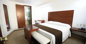 A hotel room with a bed, bedside table, chair, and a small desk with a telephone. - Hotel GS Jerocs Tlaxcala (Tlaxcala)