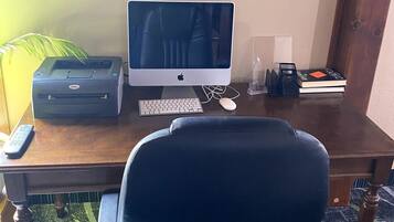 A home office setup with a desk, a computer, a printer, a keyboard, a mouse, a chair, a framed motivational quote, a lamp, and a bookshelf with books.