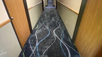 A hotel corridor with a patterned carpet, wooden doors, and a sign indicating a cottage suite.