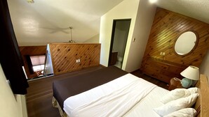 A bedroom with a large bed, wooden headboard, and a wooden wall with a circular mirror.