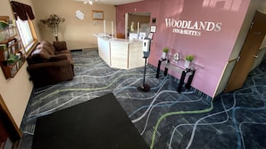 A reception area with a reception desk, a brown sofa, a glass table with decorative items, and a patterned carpet.