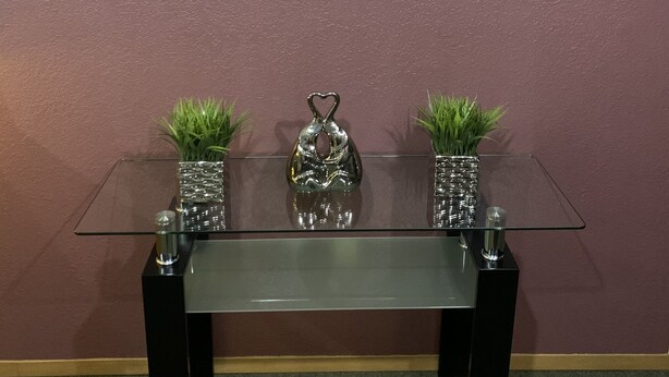 A reception desk with a sign reading "Woodlands Inn & Suites" above it. There are two potted plants on either side of the desk.