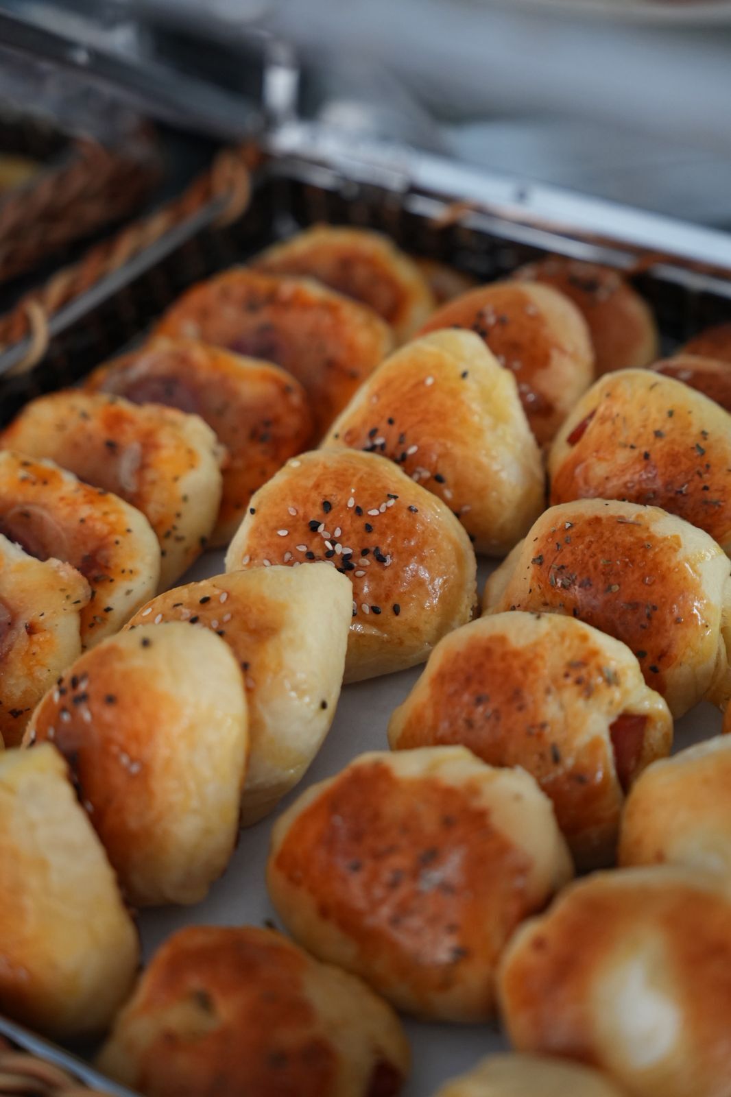 A tray of freshly baked rolls with sesame seeds.