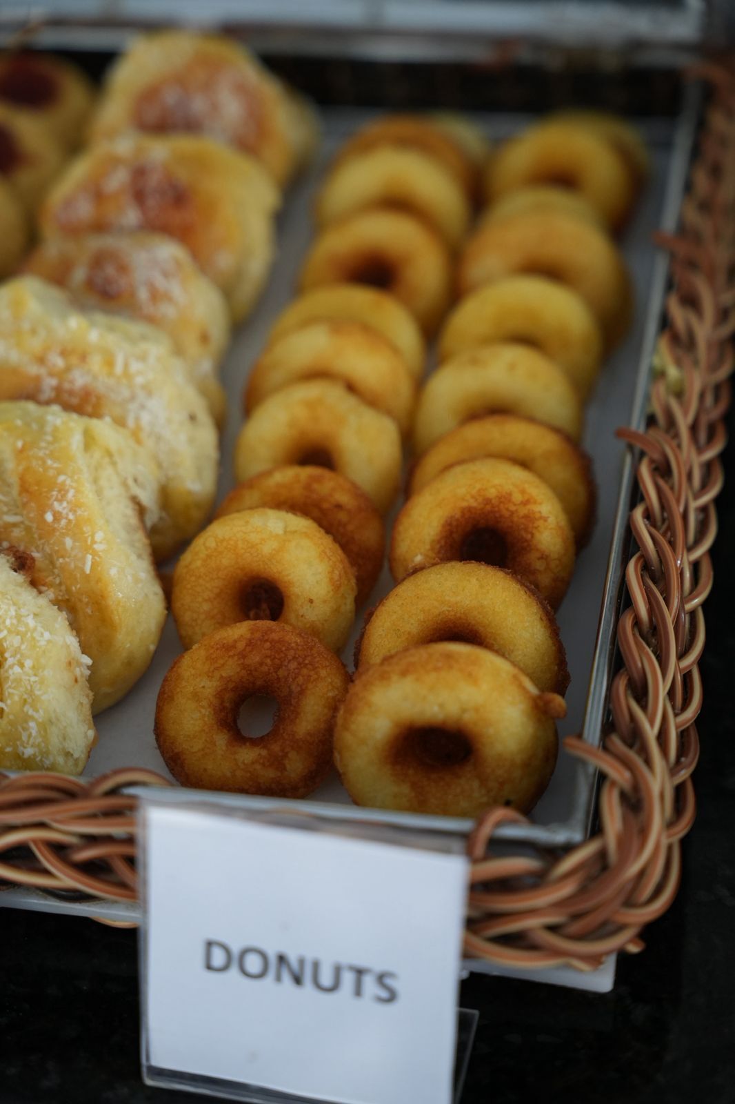 A tray of assorted donuts with a sign labeled "DONUTS".